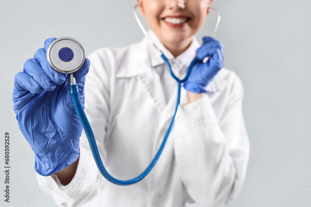 Female doctor with stethoscope on light background, closeup