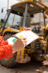 Wall Mural - a mechanical engineer is using checklist form to verify the excavator or earthmover machine (as back