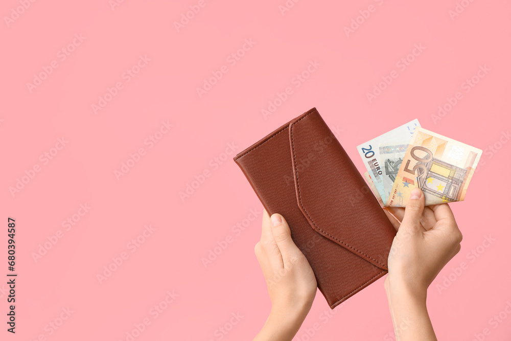Female hands with wallet and money on pink background