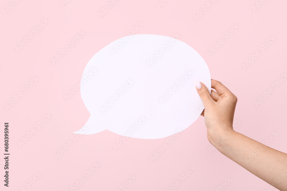 Female hand with blank speech bubble on pink background