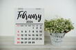 February 2024 monthly calendar with vintage alarm clock on wooden background