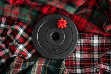 Wall Mural - Dumbbell barbell weight plate with bow. Exercise equipment Christmas gift idea. Healthy fitness winter holiday season composition on tartan plaid patterns. Gym workout and sport training flat lay.