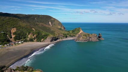 Wall Mural - piha volcanic beach new zealand. drone pulls back to reveal lion rock in foreground.