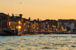 Venice sunset with restaurant tables on embankment in evening light