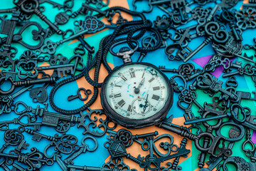 The concept of symbolism. Antique rotten pocket watch with Bronze ornamental keys on a background of multicolored paper sticky notes