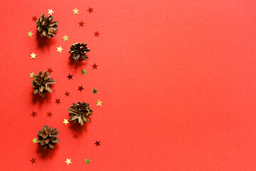 Wall Mural - red christmas background. top view photo of christmas tree cones and gold and red star ornaments wit