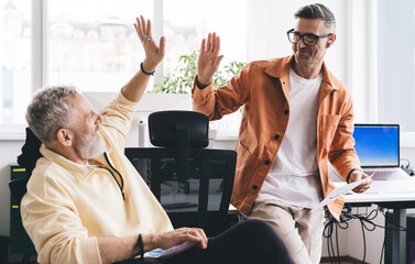 Wall Mural - Caucasian male entrepreneurs with documents giving five as deal agreement during work day in office entreprise