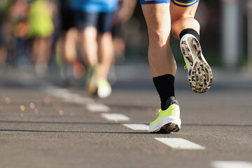 Wall Mural - Marathon runners running on city road, large group of runners, close-up legs runners running sport marathon, male jogging race in asphalt road, athletics competition