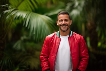 Portrait of a satisfied man in his 40s sporting a stylish varsity jacket against a lush tropical rainforest. AI Generation
