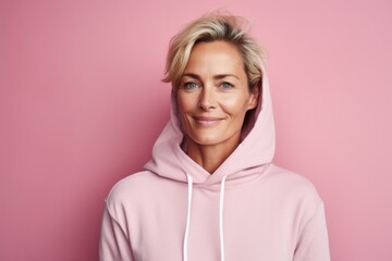 Sticker - Portrait of a satisfied woman in her 40s sporting a comfortable hoodie against a soft pink background. AI Generation