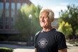 © CogniLens - Portrait of a grinning man in his 70s sporting a technical climbing shirt against a modern university campus background. AI Generation