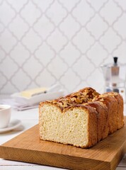 Wall Mural - Butter brioche bread sprinkled with almond petals on a wooden board on a light concrete background. Wheat bread recipes.