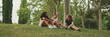 Three girls friends pre-teenage sit on the grass in the park and emotionally talking. Three teenagers on the outdoors