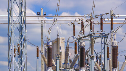 Many high voltage electrical component and insulators with electric pylon in power substation against cloudy sky background