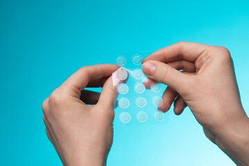 close-up round acne patch on finger on blue background. acne patches for treatment of pimple and ros