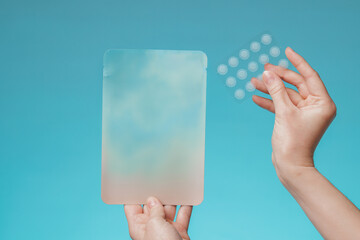 close-up round acne patch on finger on blue background. acne patches for treatment of pimple and ros