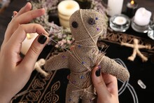 Woman Stabbing Voodoo Doll With Needle At Table, Closeup. Curse Ceremony