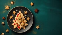  A Plate Of Cookies Decorated Like A Christmas Tree With Red Berries And Star Shaped Cookies On A Green Surface With Star Shaped Cookies On The Side Of The Plate And On Top Of The Plate.