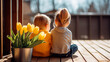 © Mariia - First love, rear view, children sitting next to each other on a veranda decorated with tulips, a boy and a girl. First date. Children's friendship. Spring at the dacha