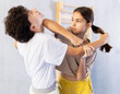 Children in sparring improve skill of performing strangulation and neutralizing enemy during krav maga class. Pupils strike out at mandible and body at self-defense lesson