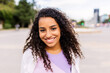 © Xavier Lorenzo - Happy young latin american girl smiling at camera standing at city street. Outside portrait of joyful beautiful woman over urban background.