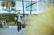 © Alliance - woman worker in business district using phone and walking