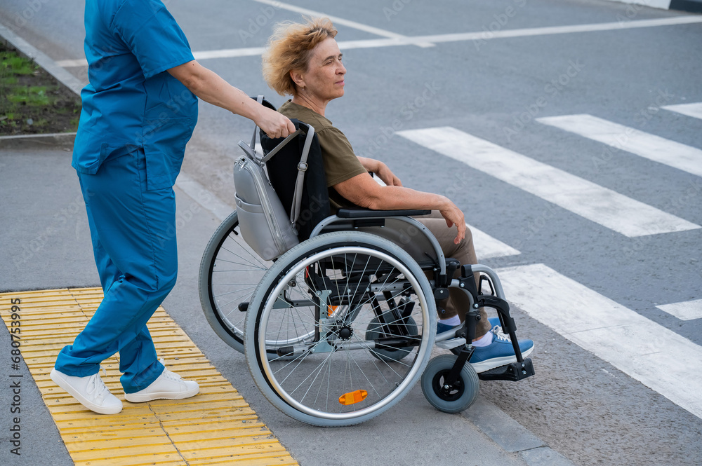 Profile of a nurse helping an elderly woman in a wheelchair cross the ...