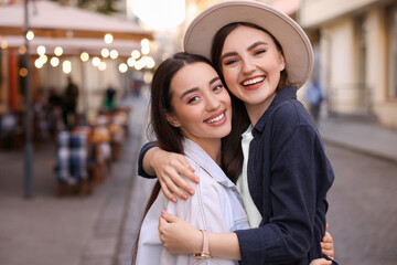 Wall Mural - Portrait of happy friends hugging on city street