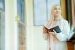 © maya1313 - The image of an Asian Muslim woman in the Islamic religion in hijab in cream color. reading the Quran and having a happy Staying in a beautiful mosque, Arabic word translation: The Holy Al Quran.