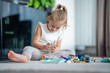 Smiling Little girl playing with small constructor toy on floor in home, educational game, spending leisure activities time concept