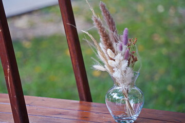 Wall Mural - A vase with dried flowers on a wooden shelf.