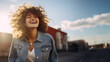 Happy and beautiful young caucasion woman wearing denim jacket enjoys sunny summer day smiling with flying hair, sunshine, blue skies, white clouds, low angle shot, copy space, 16:9