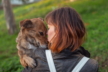 Young woman walking her mongrel dog. Lifestyle with dog. Attractive young woman in casual clothes cuddling with her beloved dog