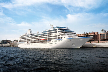 A large cruise ship stands on the pier with the city in the background.