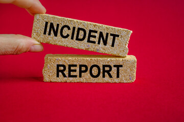 Security and insurance concept. Brick blocks with the inscription - Incident report on beautiful red background. Businessman hand. Copy space.