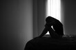 © Tinnakorn - Silhouette of depressed woman sitting in bedroom Beset by health problems accumulated stress Relationship problems.