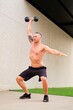 Strong man doing dumbbell squat snatch in a outdoor fitness gym. Cross Fit, fitness and sport.