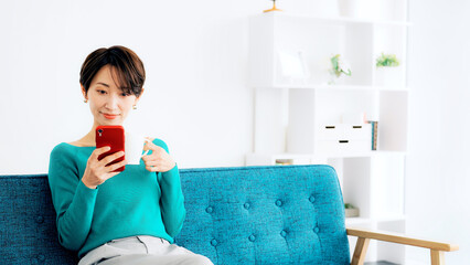 Leinwandbilder - リビングでスマホを見る女性