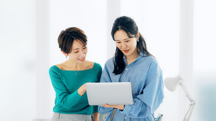 Leinwandbilder - オフィスでノートパソコンを見ながら話す二人の女性