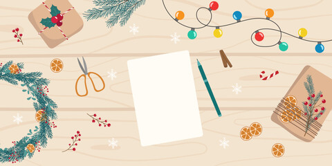 Christmas preparation top view background. Christmas decorations, garland and white blank sheet for writing a list, wishes, card, letter on light wooden table. Template for holiday design
