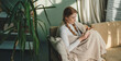 Red haired woman studying from home in comfortable warm white winter blanket, writing ideas on a clipboard. Learning at home. Beautiful young woman sitting on
