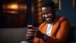 © CStock - Portrait of happy bearded African businessman using phone while sitting on sofa at modern home