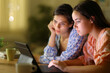 © PheelingsMedia - Two women checking tablet in the night