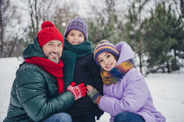 Poster - Photo of good mood cheerful little child wife husband dressed coats cuddling together outdoors urban forest park