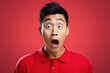 Surprised Asian man in red shirt looking at camera with open mouth