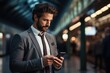 © sirisakboakaew - young elegant businessman is leaning on a pillar at station and waiting for transport while using his phone.