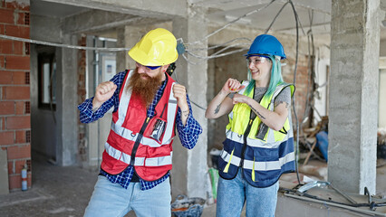 Wall Mural - Man and woman builders smiling confident dancing at construction site