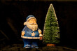 Weihnachtsmann vor verschneitem Tannenbaum, schwarzer Hintergrund