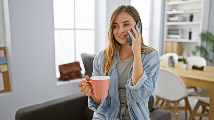 Canvas Print - Vibrant, confident blonde boss woman sparking success with smartphone talk & enjoying espresso in elegant office interior