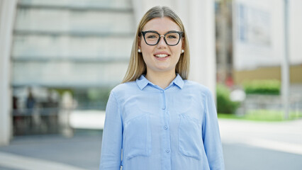 Wall Mural - Young blonde woman business worker smiling confident standing at street